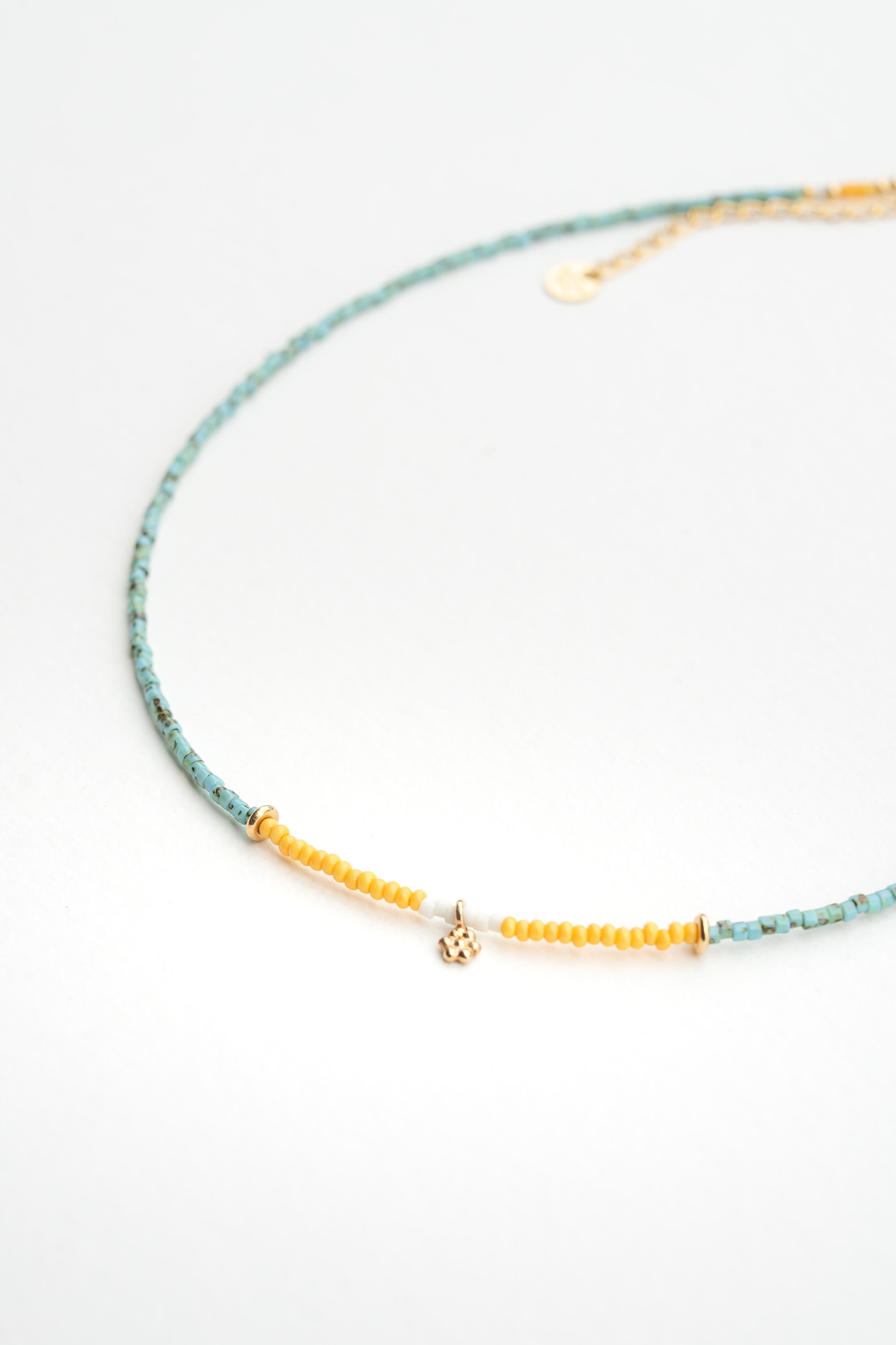 Collier ras de cou en perles de rocaille turquoises avec touches crème et jaune orangé et pampille dorée à l’or fin Byciclou