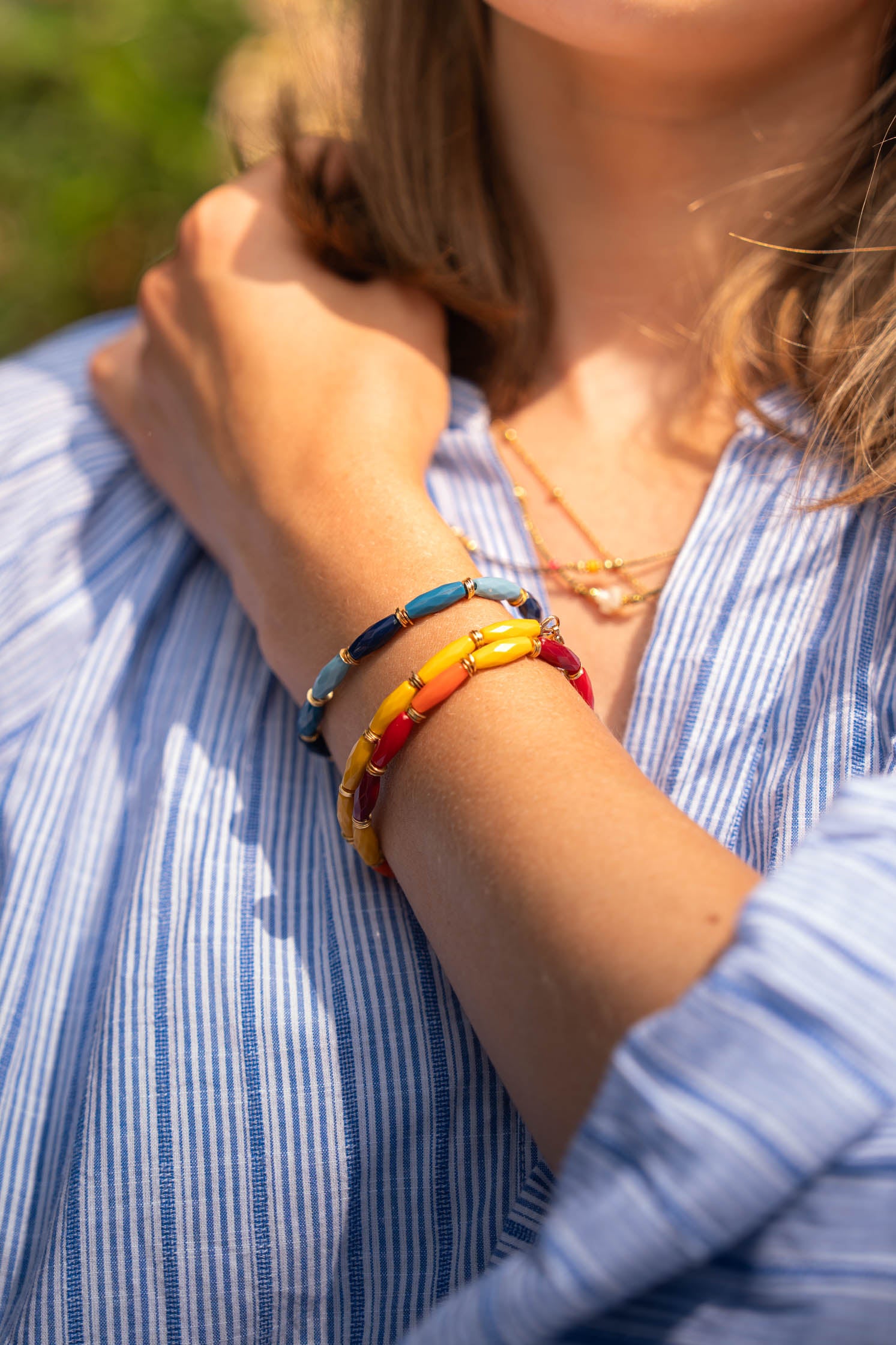Mix de bracelets colorés en perles de bohème jaunes, orange et rouges avec touches dorées portés Byciclou