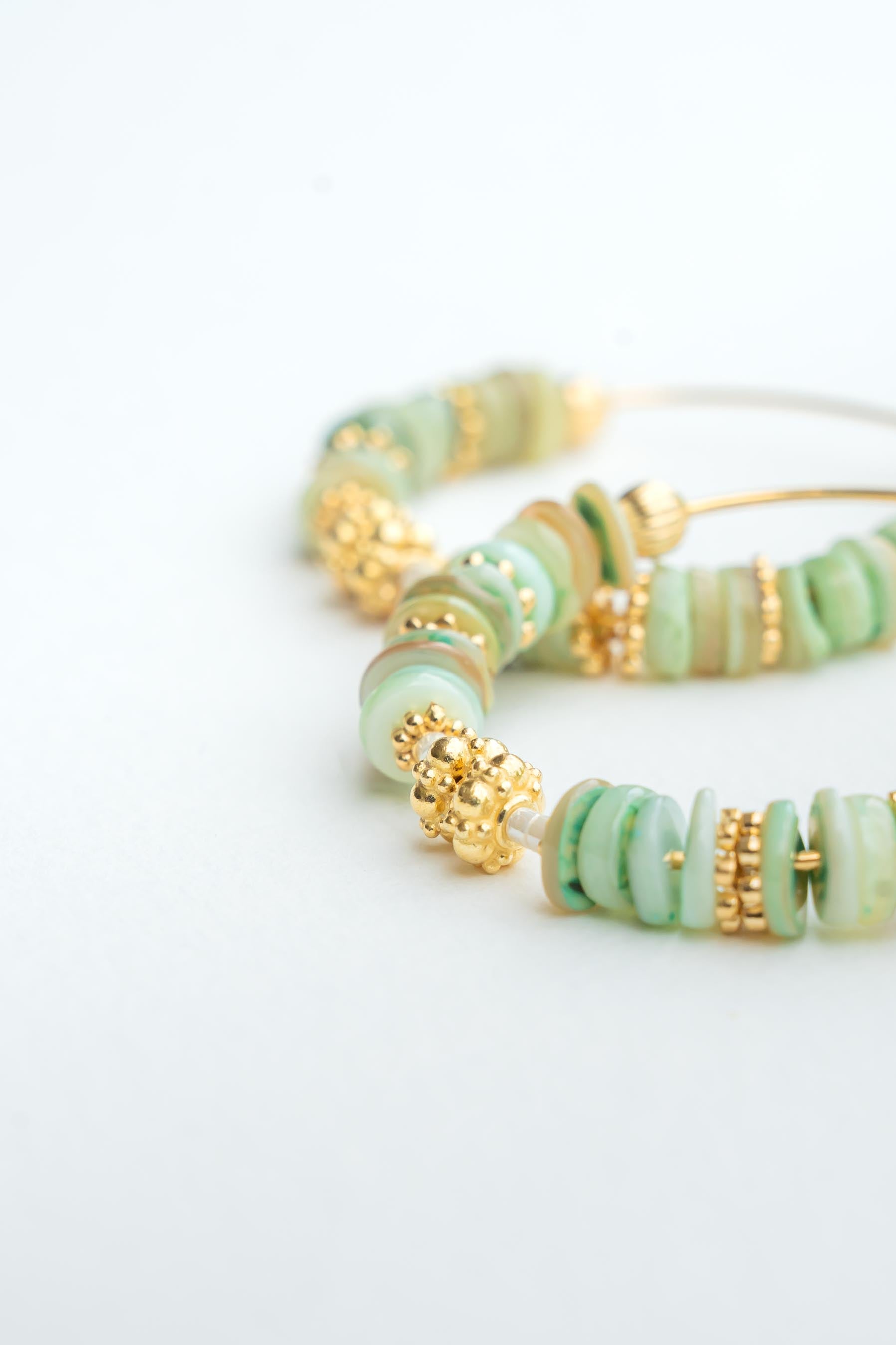 Boucles d’oreilles créoles dorées à l’or fin avec perles de coquillages teintées vert et perles dorées Byciclou