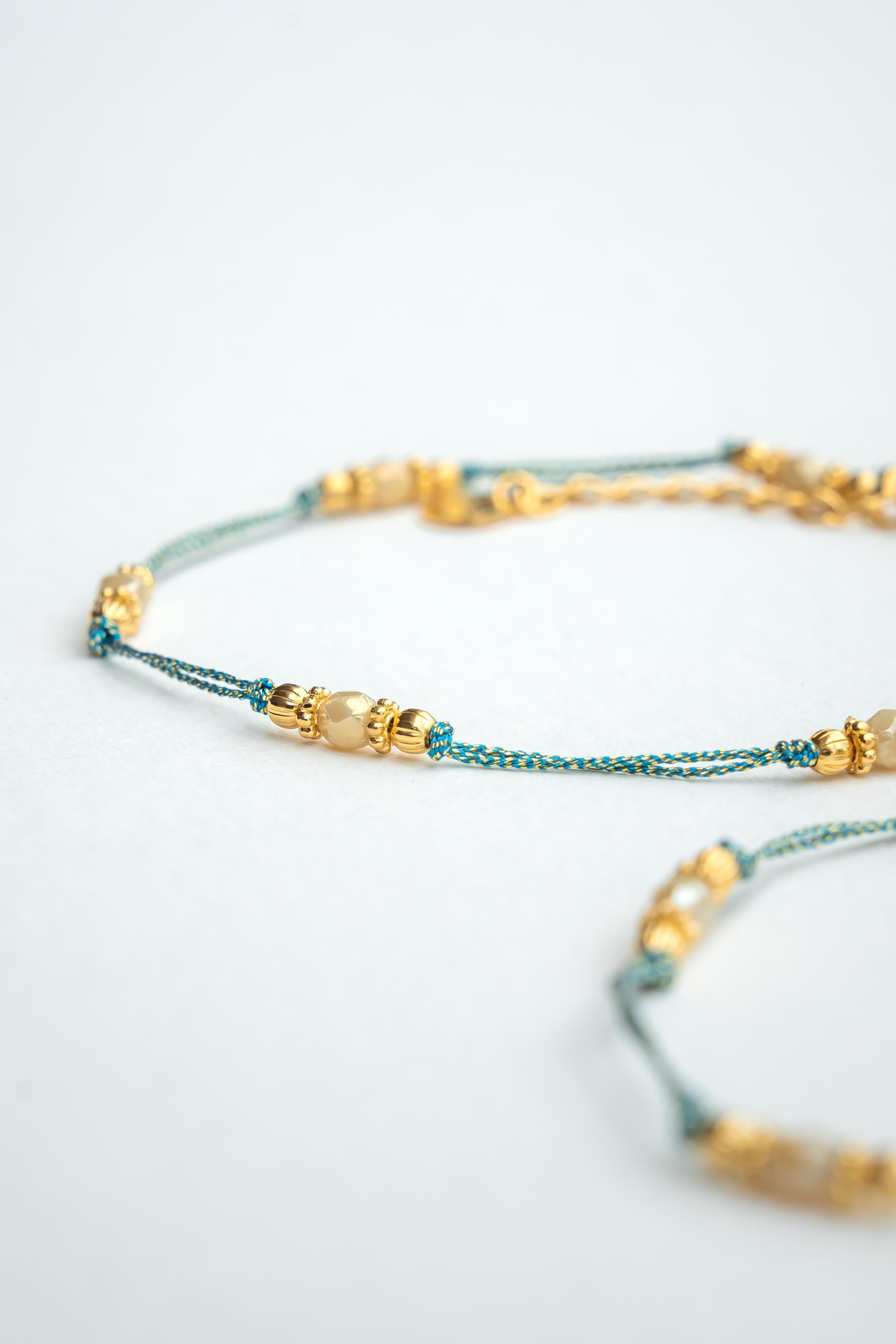 Bracelet en fil métallisé doré avec perles bleues et éclats d’or fin Byciclou