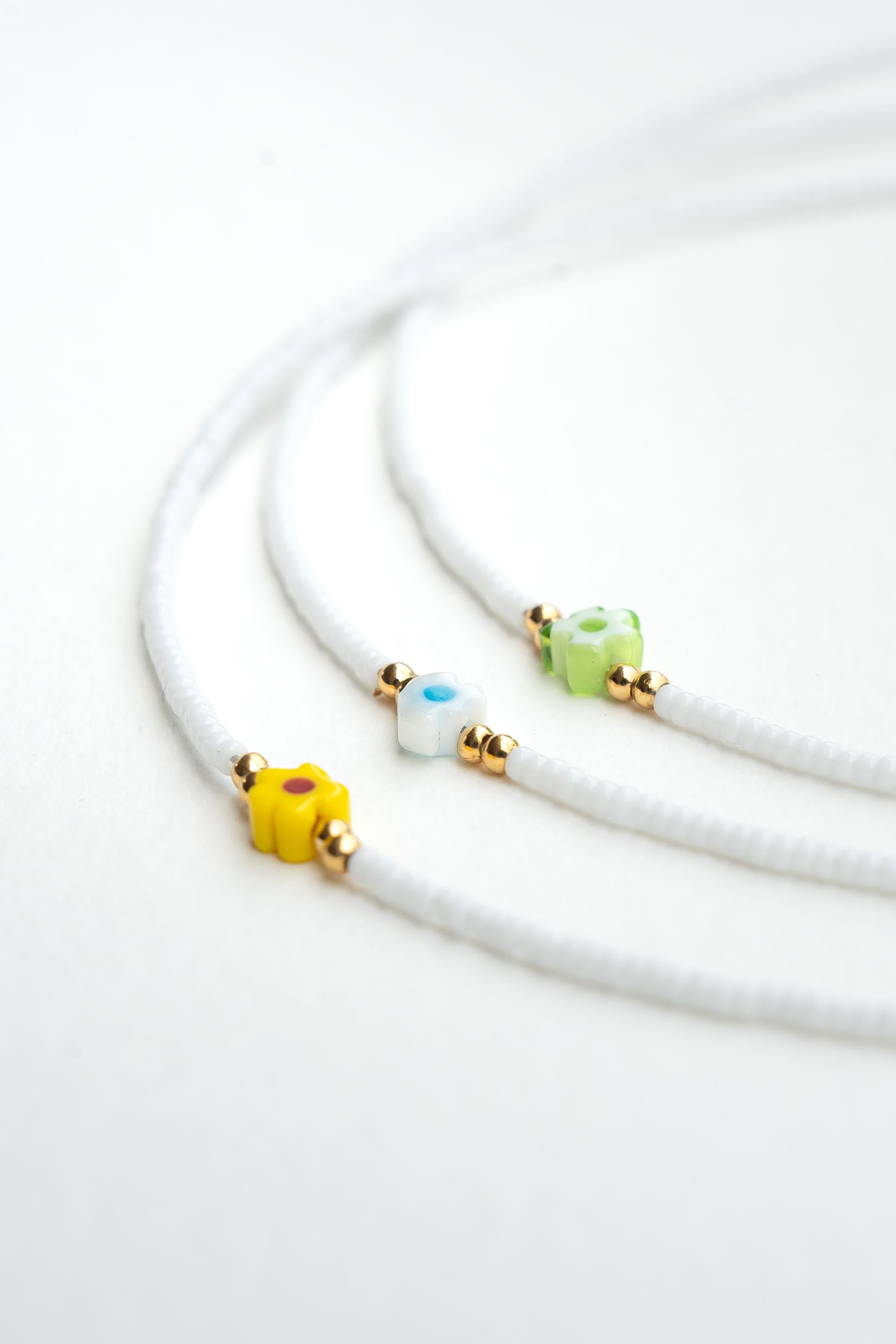 Collier ras de cou enfant en perles de rocaille blanches avec perles fleur colorées et perles dorées Byciclou